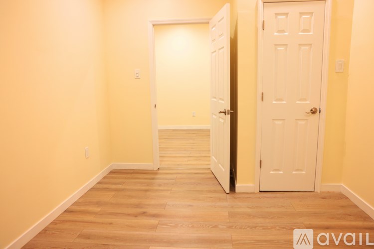 A hallway with two doors and wooden floors.