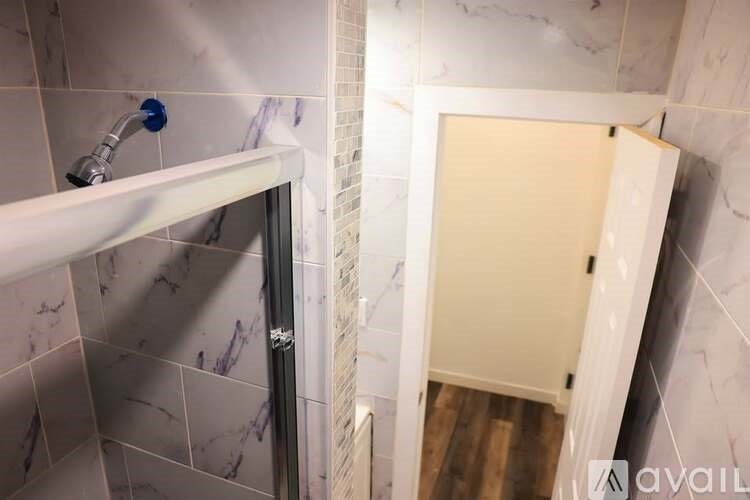 A white bathtub with a shower head and a white door.