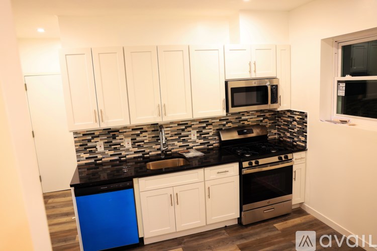 A kitchen with white cabinets and a black countertop.