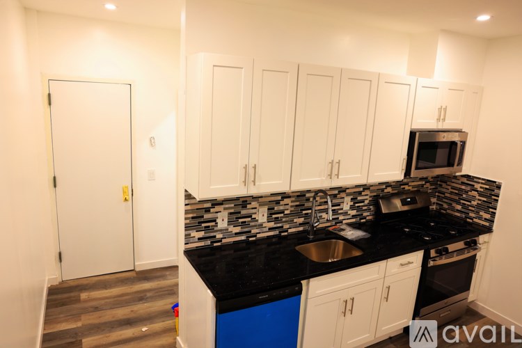A kitchen with white cabinets and a black countertop.