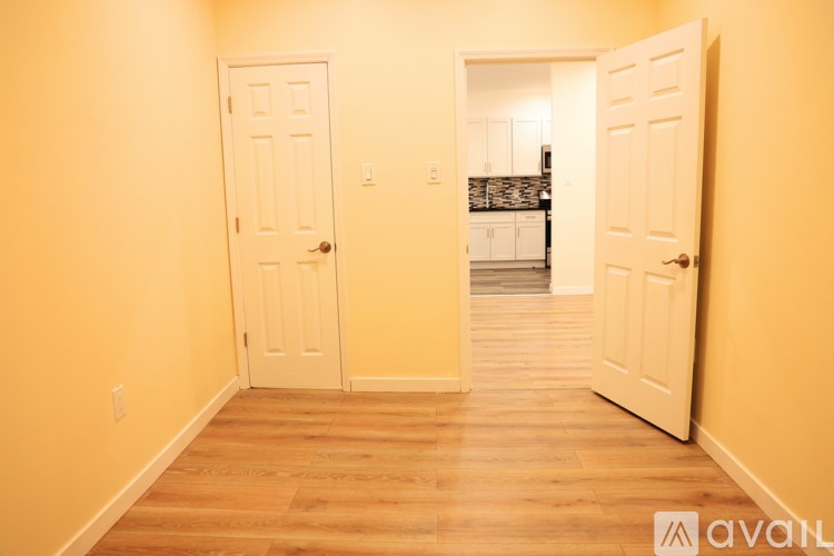 A room with two white doors and a wooden floor.