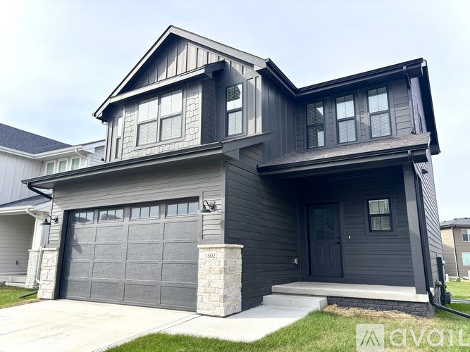 A modern house with a grey exterior and a black garage door.