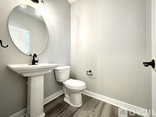 A white sink and toilet in a bathroom with a round mirror.