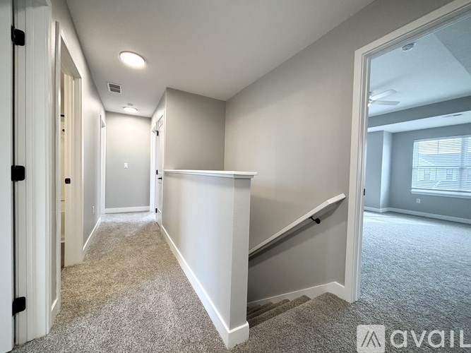A hallway with a carpeted floor and white walls.