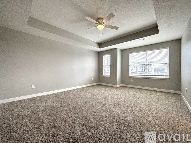 A room with a ceiling fan and carpeted floor.