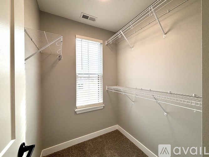 A room with a window and a carpeted floor.