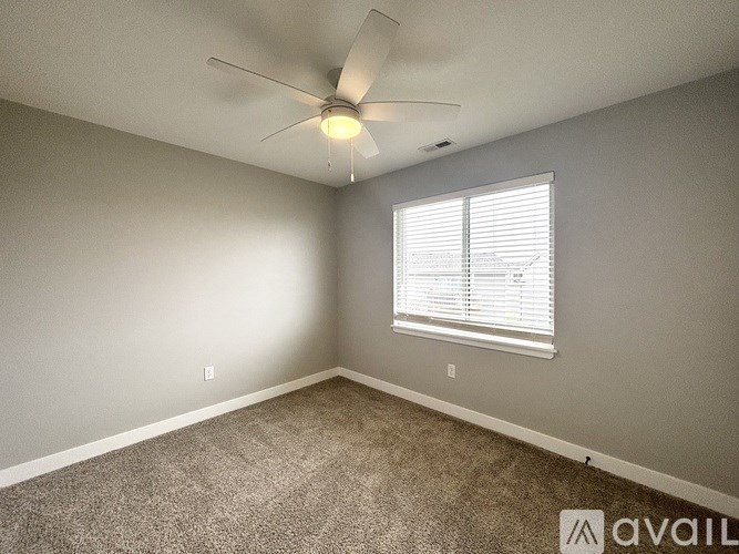 A room with a ceiling fan and a window with blinds.