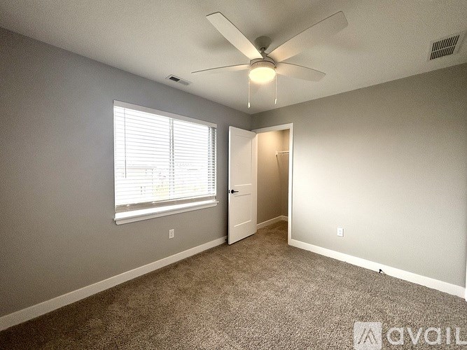 A room with a ceiling fan and a window with blinds.