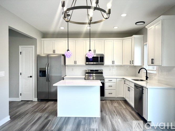 A modern kitchen with a white island and stainless steel appliances.