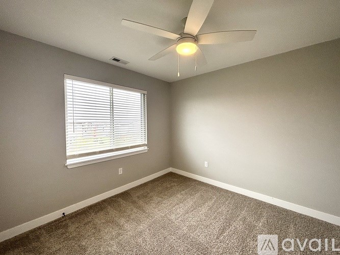 A room with a ceiling fan and a window with blinds.