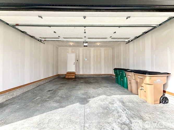 A large empty warehouse with a white wall and a door in the middle.