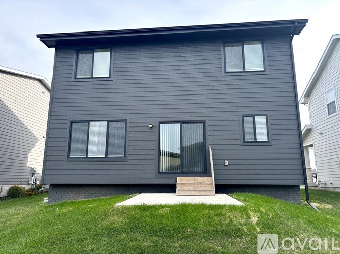 A grey house with a front yard and a small porch.