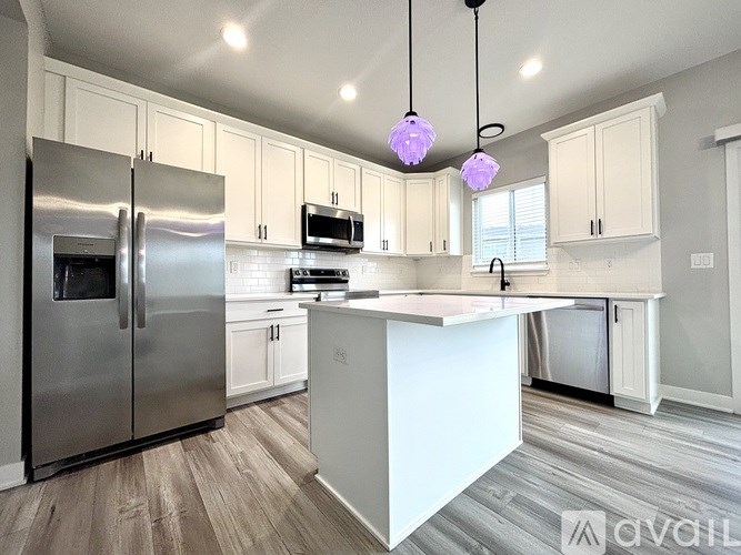 A modern kitchen with a white island and stainless steel appliances.
