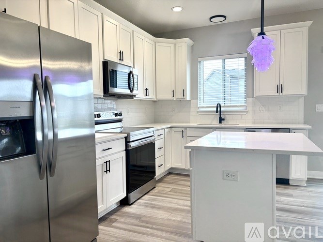 A modern kitchen with white cabinets and stainless steel appliances.
