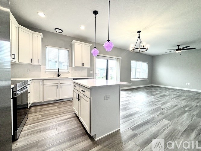 A modern kitchen with white cabinets and a wooden floor.