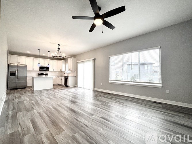 A spacious kitchen with a ceiling fan and wooden flooring.