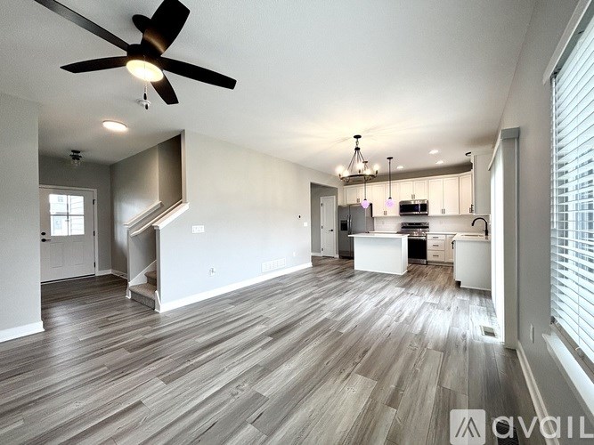 A modern kitchen with a wooden floor and a ceiling fan.