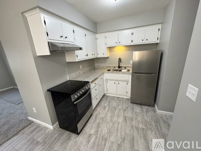 A kitchen with a black stove top oven and a silver refrigerator.