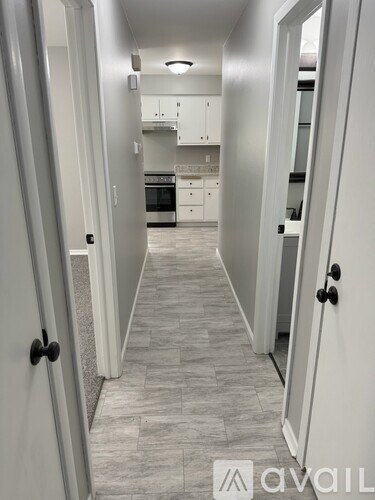 A hallway with a tiled floor leads to a kitchen.