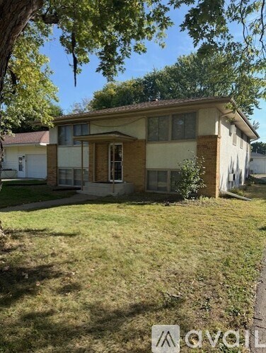 A house with a white door and windows is surrounded by a grassy area.