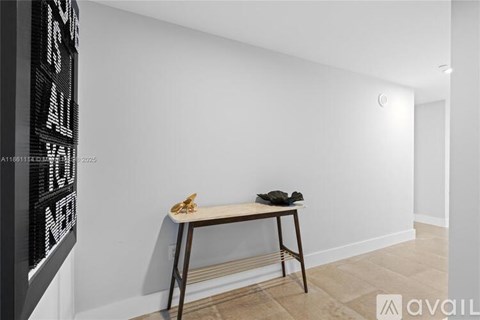 A room with a white wall and a wooden table with a black object on it.