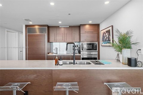 A modern kitchen with a stainless steel refrigerator, microwave, and oven.