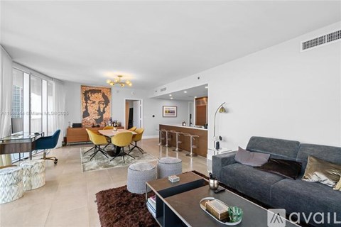 A living room with a grey couch, a yellow table, and a painting on the wall.
