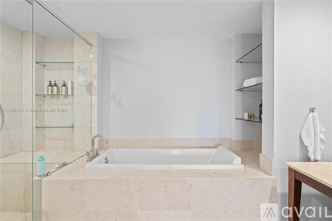 A modern bathroom with a glass shower door and a white tub.