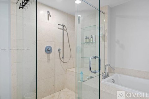 A bathroom with a glass shower door and a glass-fronted bathtub.