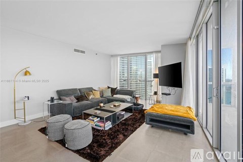 A living room with a grey sofa, a coffee table, and a yellow throw pillow.