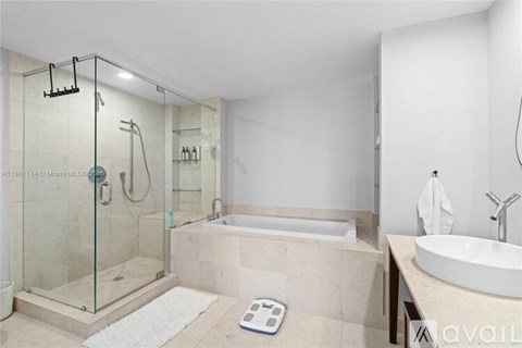 A modern bathroom with a glass shower stall, a bathtub, and a sink.