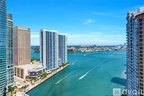 A view of a cityscape with tall buildings and a body of water with boats.