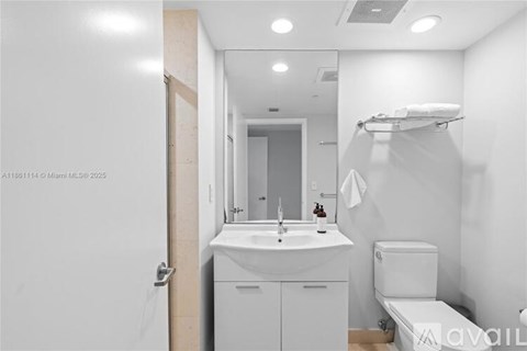 A white bathroom with a sink, toilet, and mirror.
