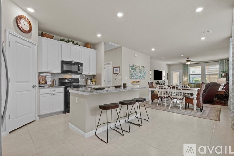 A kitchen with white cabinets and a large island with bar stools.
