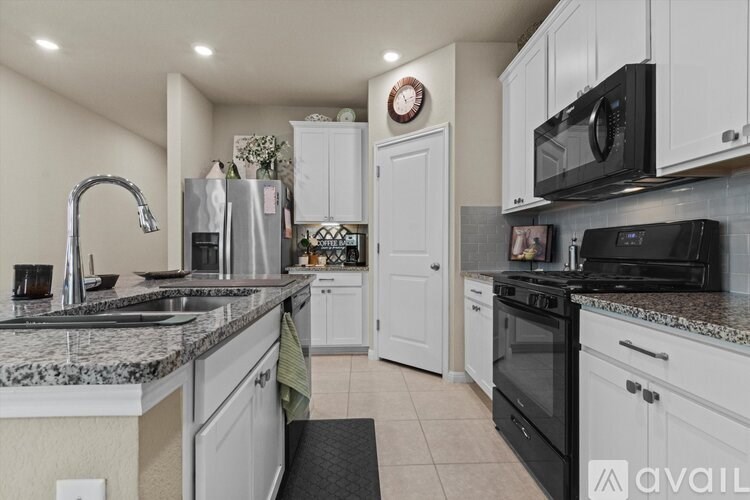 A kitchen with black appliances and white cabinets.