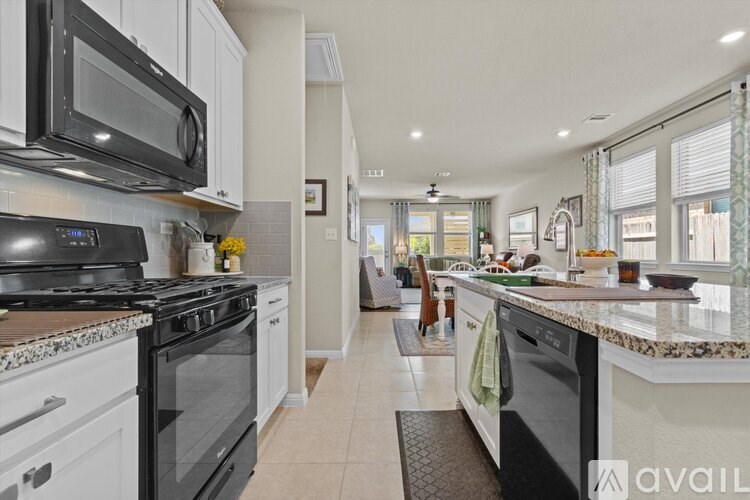A kitchen with black appliances and white cabinets.