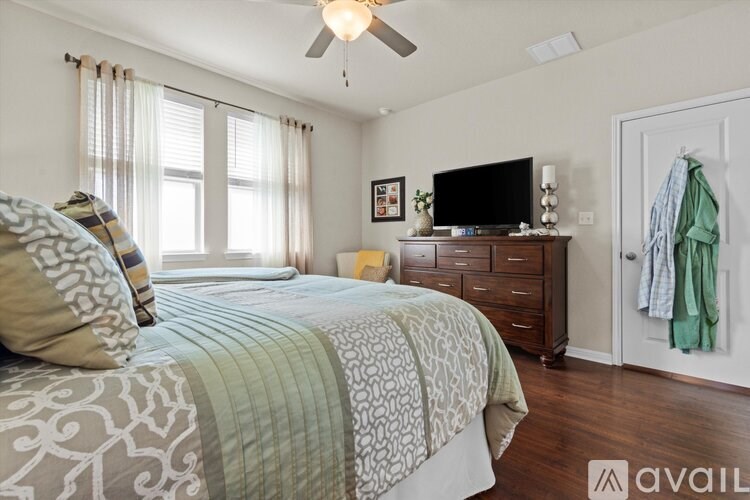 A bedroom with a large bed and a television on a dresser.