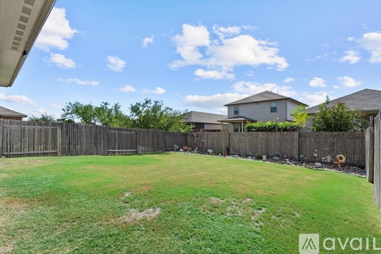 A backyard with a wooden fence and a house in the background.