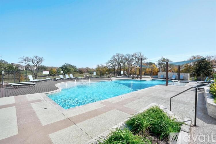 A large outdoor swimming pool surrounded by a tiled deck and lounge chairs.