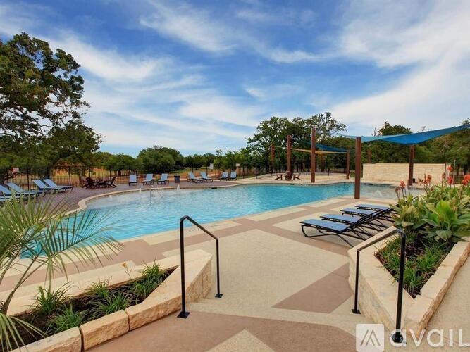 A pool surrounded by a concrete patio and a metal railing.