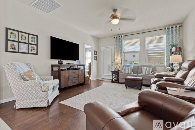 A living room with a white chair and brown leather couch.