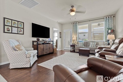 A living room with a white chair and brown leather couch.