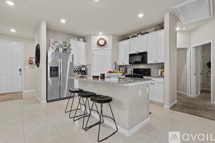 A kitchen with white cabinets and a marble countertop.
