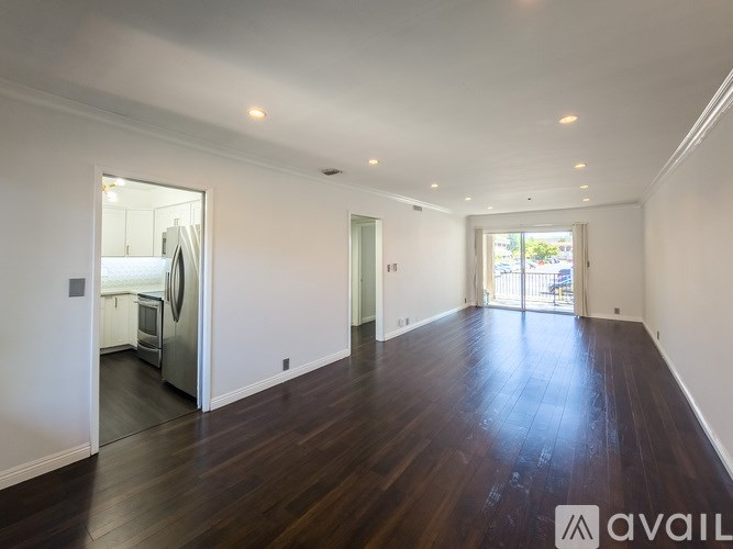 A spacious room with wooden floors and white walls.