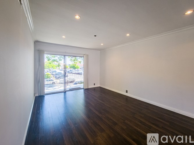 A room with wooden floors and white walls, with a window and sliding glass door.