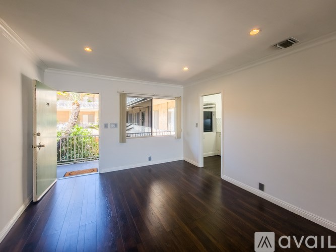 A spacious room with wooden floors and white walls.