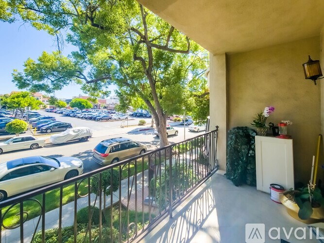 A balcony with a black railing and a tree in the background.