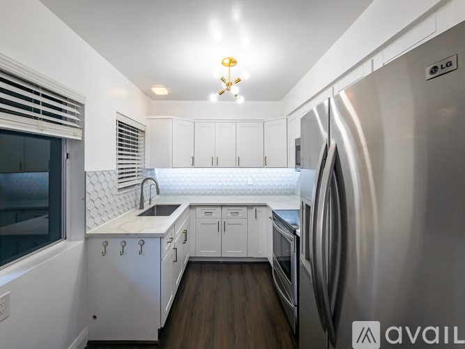A modern kitchen with a stainless steel refrigerator and white cabinets.