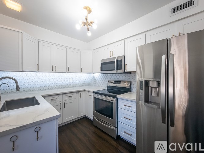 A kitchen with white cabinets and a stainless steel refrigerator.