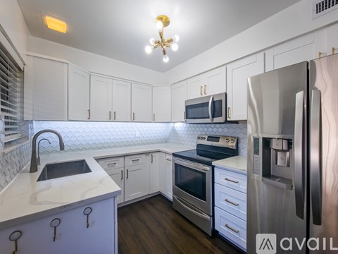 A kitchen with white cabinets and a stainless steel refrigerator.